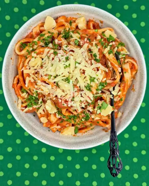 Ratatouille Pasta Sauce tossed through cooked, homemade pasta and topped with freshly grated parmesan cheese. Served in a bowl with a fork.